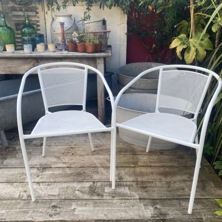 La paire de fauteuils de jardin blancs en métal, placée sur une terrasse en bois et entourée de plantes, offre un espace convivial et idéal pour profiter du plein air. Brocante 93