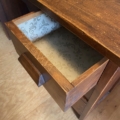 Un tiroir ouvert en bois tapissé de papier à motifs est fixé au Bureau vintage 1960, posé sur un plancher en bois. Brocante 93