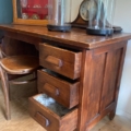 Le Bureau maitre d'école 1960, un bureau vintage en bois avec trois tiroirs ouverts, une chaise, une horloge et des coupoles en verre sur le dessus, évoque le charme classique d'une salle de classe. Brocante 93