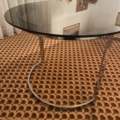 La Table verre & chrome 1970 est posée sur une moquette brune à motifs près de rideaux blancs transparents, offrant un look rétro intemporel. Brocante 93