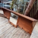 Porte-manteaux bois 1940 avec miroir central, placé à l'extérieur sur une terrasse en bois, près de plantes et d'un arbre. Brocante 93