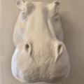 La sculpture de tête d'hippopotame blanche "Trophées muraux résine" apporte une touche saisissante en tant que décoration murale sur un mur beige, face à l'avant. Brocante 93