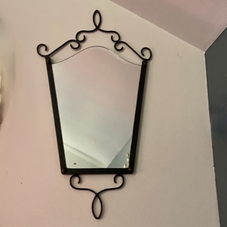 Le Miroir fer forgé vintage 1950 présente un cadre en métal noir avec d'élégantes volutes, apportant un charme vintage et une sophistication à tout mur de couleur claire. Brocante 93
