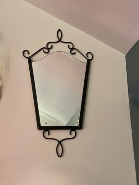 Le Miroir fer forgé vintage 1950 présente un cadre en métal noir avec d'élégantes volutes, apportant un charme vintage et une sophistication à tout mur de couleur claire. Brocante 93