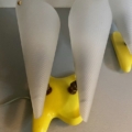 Paire d'appliques vintage 1960 : base de lampe jaune avec deux abat-jour coniques en verre dépoli, vus d'en haut sur une surface grise - mettant en valeur le design vintage intemporel. Brocante 93