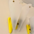 La Paire d'appliques vintage 1960 est une applique murale jaune avec deux abat-jours en verre blanc texturé en forme d'aile, inspirée du design des années 1960. Brocante 93