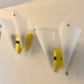 Paire d'appliques vintage 1960 : deux appliques murales jaunes et blanches aux abat-jours courbés translucides décorent un mur blanc. Brocante 93