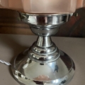 Gros plan sur une base de Lampe Art Déco 1930 en argent brillant avec un abat-jour en verre rose sur une surface beige. Brocante 93