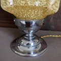 Gros plan sur la base de la Lampe verre 1950 avec chrome et verre jaune texturé, à côté d'un cordon torsadé jaune. Brocante 93