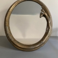 Le Miroir Art Déco 1930 présente un design rond avec un cadre en bronze orné et une femme sculptée sur le côté droit, présenté sur une surface grise. Brocante 93