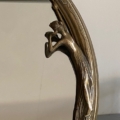 Miroir Art Déco 1930 : Cadre décoratif en bronze représentant une femme sculptée dans une robe fluide s'appuyant gracieusement sur le bord, évoquant l'élégance intemporelle des années 1930. Brocante 93
