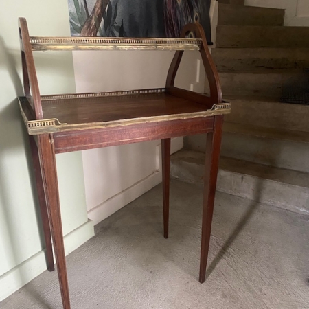 Une table d'appoint de 1940 aux côtés surélevés se trouve près d'un escalier et d'un mur décoré d'une œuvre d'art représentant un paon. Brocante 93