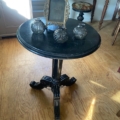 Le Guéridon Napoléon III, une table d'appoint ronde et noire, est orné de trois ornements en verre et d'une photo encadrée d'argent, et repose sur un plancher en bois. Brocante 93