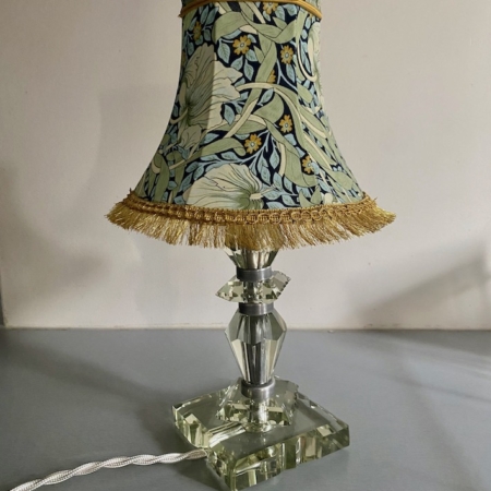 Une Lampe pied en verre vintage 1940 avec un abat-jour à motif floral et une base en cristal repose sur une surface grise. Brocante 93