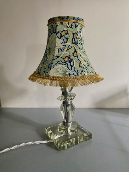 Une Lampe pied en verre vintage 1940 avec un abat-jour à motif floral et une base en cristal repose sur une surface grise. Brocante 93