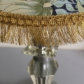 Gros plan sur la Lampe pied en verre vintage 1940, dotée d'un abat-jour floral avec des franges dorées et d'une base en verre facetté, évoquant un style vintage élégant. Brocante 93