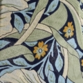 Motif de tissu floral avec des fleurs jaunes, des feuilles vertes et des accents bleus sur un fond sombre. Idéal pour accompagner une Lampe pied en verre vintage 1940 ou d'autres éléments de décoration classiques. Brocante 93