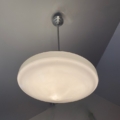 La suspension verre & opaline 1940 est un plafonnier moderne inspiré des années 1940, avec un abat-jour rond en verre opalin et une tige en métal, monté sur un plafond gris. Brocante 93