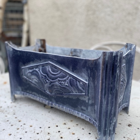 La Jardinière Art Déco 1930 est une pièce rectangulaire ancienne et ornée de motifs en relief, présentés sur une surface perforée de couleur claire. Brocante 93
