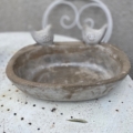 Le Bain oiseaux pierre 1960, orné de deux sculptures d'oiseaux sur son rebord et présenté sur une table blanche usée par le temps, ajoute un charme vintage. Brocante 93