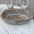 Le Bain oiseaux pierre 1960 est orné de deux petites sculptures d'oiseaux sur le bord et est présenté à l'extérieur sur une table blanche rustique. Brocante 93