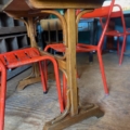 La table de bistrot Formica rouge 1950, dotée d'une base solide, est associée à des chaises en métal rouge vintage et posée sur un sol en bois dans un cadre confortable. Brocante 93