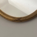 Gros plan sur le Miroir à entrelacs, un miroir rond avec un cadre doré et un "X" sculpté dans le bas. Brocante 93