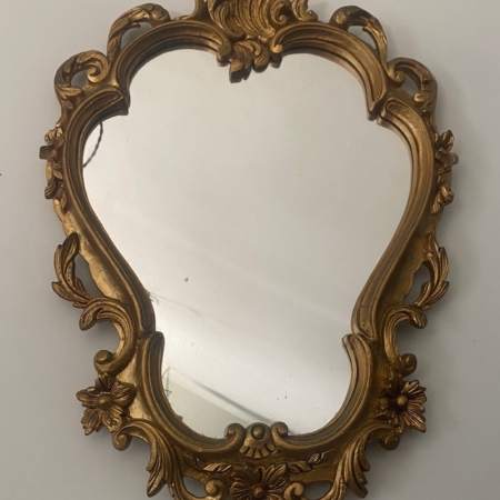 Le Miroir Rococo 1960 présente un cadre doré décoratif avec des motifs floraux et des volutes complexes. Il respire l'élégance vintage et le style rococo classique lorsqu'il est accroché gracieusement à un mur. Brocante 93