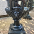 Gros plan d'un vase en métal foncé de la "Paire de vases Médicis XXème siècle", présentant une tête de lion et une anse, reposant sur une base carrée à l'extérieur. Artisanat français du 20e siècle. Brocante 93