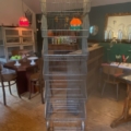 Un grand porte-bagages vide de Casiers d'épicerie Caddie 1970 sur roulettes se trouve dans une pièce confortable d'inspiration rétro, meublée de pièces en bois chaudes. Brocante 93