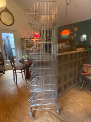 Le Caddie 1970 de Casiers d'épicerie est une haute étagère métallique avec cinq étagères inclinées sur roulettes, parfaite pour ajouter une touche vintage à une pièce confortable. Brocante 93