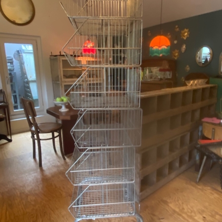 Le Caddie 1970 de Casiers d'épicerie est une haute étagère métallique avec cinq étagères inclinées sur roulettes, parfaite pour ajouter une touche vintage à une pièce confortable. Brocante 93