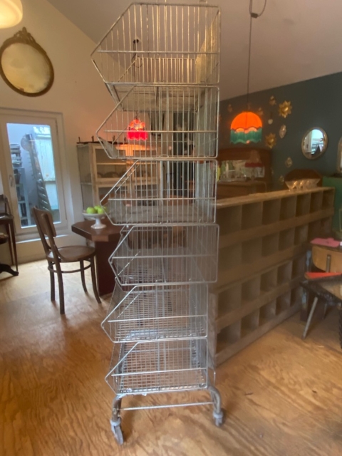Le Caddie 1970 de Casiers d'épicerie est une haute étagère métallique avec cinq étagères inclinées sur roulettes, parfaite pour ajouter une touche vintage à une pièce confortable. Brocante 93