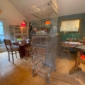 Le Caddie 1970 de Casiers d'épicerie, un haut panier métallique sur roulettes, ajoute un charme vintage à la salle à manger confortable. Brocante 93