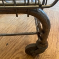 Gros plan sur une roue de caddie rouillée sur bois, évoquant les Casiers d'épicerie Caddie 1970 de l'époque des casiers vintage. Brocante 93
