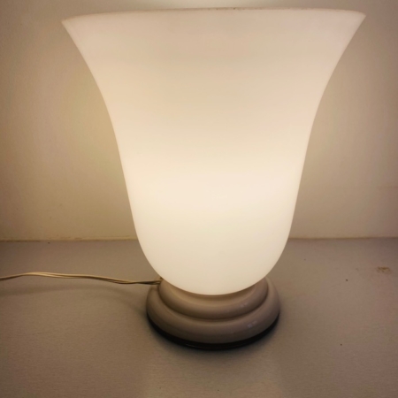 Une lampe Art déco de 1930, à la lueur douce, réalisée en verre opalin blanc et dotée d'un socle arrondi, repose avec élégance sur une surface claire, incarnant toute la sophistication intemporelle du style Art déco des années 1930. Brocante 93