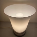 La lampe opaline Art déco de 1930, avec son design blanc en forme de cône inspiré du style Art déco des années 1930, diffuse une lumière douce et chaleureuse sur les murs et les surfaces aux tons neutres. Brocante 93