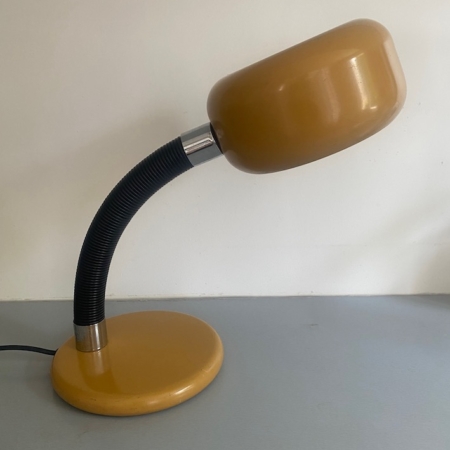 Une lampe de bureau « Lampe berlinoise 1970 » de couleur jaune, dotée d'un bras flexible noir et évoquant le design épuré des années 1970, repose sur une surface gris clair devant un mur blanc. Brocante 93
