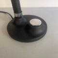 Pied de lampe noir orné d'un interrupteur à bouton argenté sur une surface grise, cordon visible à l'arrière-plan : véritable touche vintage, la « Lampe berlinoise 1970 » rappelle les designs emblématiques du milieu du siècle dernier. Brocante 93