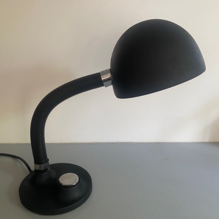 Lampe berlinoise de 1970 — cette élégante lampe de bureau noire, dotée d'un bras flexible, d'un abat-jour en forme de dôme et d'un socle rond, repose sur un support gris clair et incarne l'essence même du design du milieu du siècle, rappelant les luminaires emblématiques des années 1970. Brocante 93