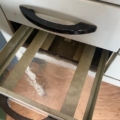Un meuble de dentiste des années 1950 s'ouvre, dévoilant un intérieur vide doté d'une doublure métallique rayée et de poignées noires, qui rappelle le mobilier vintage classique des années 1950. Brocante 93