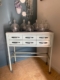 Un « Meuble de dentiste 1950 » — une armoire vintage en métal dotée de six tiroirs et surmontée de bocaux en verre — est posé contre un mur bleu et blanc. Brocante 93