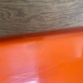 Une surface en bois côtoie une surface orange vif brillante, séparées par un bord incurvé, qui reflète l'esthétique ludique de la Table basse 1970. Brocante 93