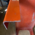 Gros plan sur la table basse 1970 en métal ou en plastique orange vif, aux bords à angle droit, posée sur un sol en bois : l'idéal pour apporter le charme des meubles vintage à votre intérieur. Brocante 93