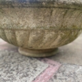 Une vasque en pierre datant de 1960 trône sur une terrasse ; sa pierre patinée et ses touches de mousse mettent en valeur la surface texturée du béton et soulignent le charme intemporel de cette pièce. Brocante 93