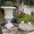 Vase Médicis blanc du XXe siècle orné de verdure, bain d'oiseaux avec deux figurines d'oiseaux, table rustique en bois et décorations métalliques représentant des oiseaux. Brocante 93