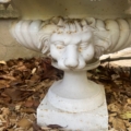 Socle de fontaine « Vasque Médicis » du XXe siècle, en pierre blanche, orné d’une tête de lion sculptée et entouré de feuilles sèches et de copeaux de bois. Brocante 93