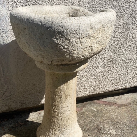 L’« Auge en pierre 1940 », un abreuvoir en pierre patinée doté d’un bassin rond et d’un socle rappelant une auge ancienne, trône avec élégance sur une surface en béton baignée de soleil. Brocante 93