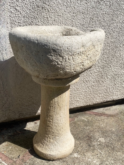 L’« Auge en pierre 1940 », un abreuvoir en pierre patinée doté d’un bassin rond et d’un socle rappelant une auge ancienne, trône avec élégance sur une surface en béton baignée de soleil. Brocante 93