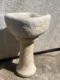 L’« Auge en pierre 1940 », un abreuvoir en pierre patinée doté d’un bassin rond et d’un socle rappelant une auge ancienne, trône avec élégance sur une surface en béton baignée de soleil. Brocante 93